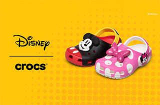 Two children's shoes, one black and red, one pink with a bow, on a yellow background with Disney and Crocs logos.